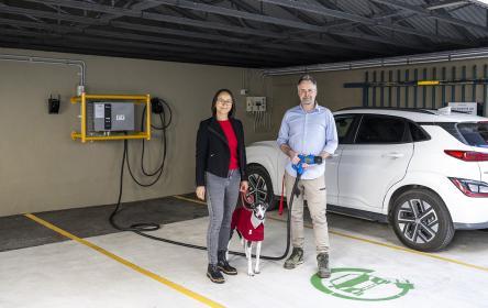Couple with dog standing in front of electric vehicle charging